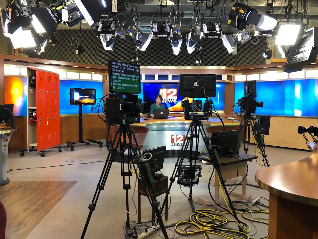 Modern TV newsroom with multiple screens and journalists